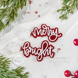 May include: Red glittery "Merry" and "Bright" cutouts with white script lettering. The festive decorations are surrounded by greenery and red berries, perfect for holiday crafts or decor.