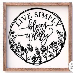 以下が含まれることがあります： 花輪と「Live Simply Bloom Wildly」というテキストが書かれた白黒の看板です。