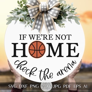May include: A white round sign with a black and white checkered bow and greenery on top. The sign says "If we're not home check the arena" with a basketball graphic in the middle.