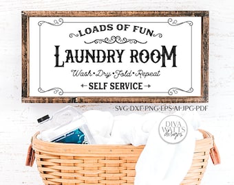 May include: A wooden sign with the text "Loads of Fun Laundry Room Wash Dry Fold Repeat + Self Service +" in black lettering. The sign is hanging on a white wall. Below the sign is a wicker basket filled with white towels and a clear plastic bottle of laundry detergent.