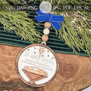 May include: A wooden Christmas ornament with a white background and brown trim. The ornament features a star, a manger scene, and the text "Oh Holy Night! The stars are brightly shining, it is the night of our dear Savior's birth."