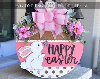 Pode incluir: Um pendurador de porta de Páscoa rosa e branco com um coelho branco, um laço rosa e o texto "Happy Easter".