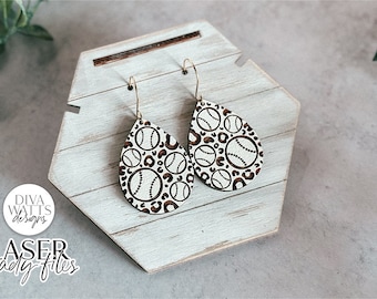 May include: A pair of teardrop-shaped earrings with a white background and a brown and white baseball pattern. The earrings are hanging from a white wooden display stand.