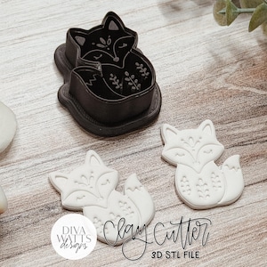 May include: A black fox-shaped clay cutter and two white fox-shaped clay cutouts featuring embossed floral and facial details. The text Diva Watts Designs Clay Cutter 3D STL File is visible in the lower portion of the image.