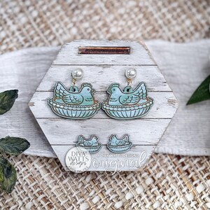 Digital SVG File Instant Download Featuring Vintage Hen Dangle Earrings In A Cottagecore Grandma Core Style, Designed For Laser Cut Earring Projects. This Earring Template SVG Shows A Charming Chicken Sitting In A Nest With Thrifted Farmhouse Appeal, Perfect For Handmade Jewelry Makers And Boutique Collections. Clean Laser Earring File Ready For Immediate Use And Creative Customization.