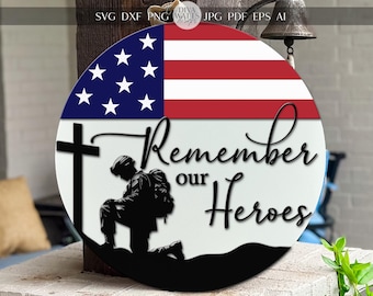May include: A round wooden sign with a silhouette of a soldier kneeling in front of a cross. The sign is decorated with an American flag and the text "Remember our Heroes".