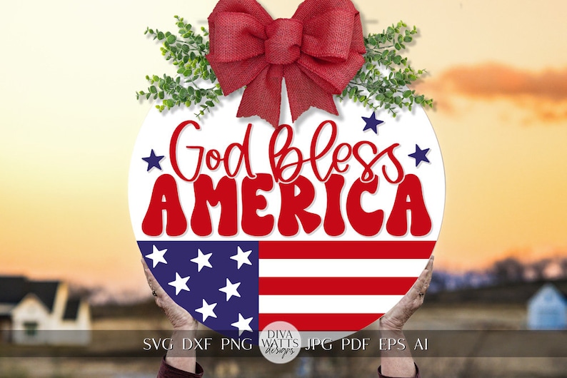 May include: A round, white sign with a red bow and green leaves at the top. The sign says "God bless AMERICA" in red letters with a blue and white American flag at the bottom.
