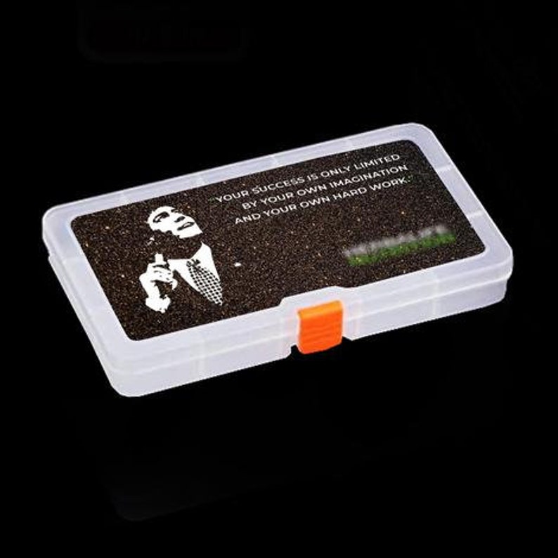 Op de afbeelding: Een transparante plastic opbergdoos met een zwart-wit afbeelding van een man met de quote "Je succes wordt alleen beperkt door je eigen verbeelding en je eigen harde werk."