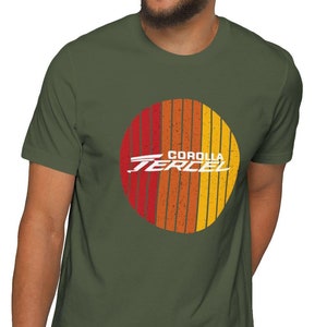 Könnte beinhalten: Ein grünes T-Shirt mit einem Retro-Sonnenstrahl-Design mit dem Text "COROLLA TERCEL" in Weiß.