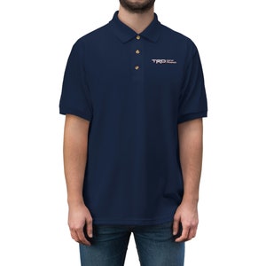 May include: A navy blue polo shirt with a small embroidered logo that says "TRO Off Road" in white and red lettering.