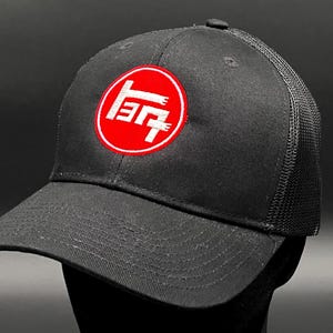 Könnte beinhalten: Schwarze Mesh-Trucker-Kappe mit einem roten Kreis und weißen japanischen Schriftzeichen, die vorne "Toyota" sagen.