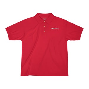 May include: Red short-sleeved polo shirt with a white embroidered logo that says "TRD OFF ROAD"