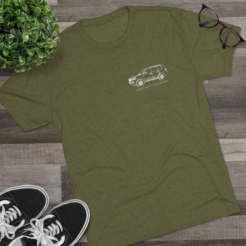 K&ouml;nnte beinhalten: Ein gr&uuml;nes T-Shirt mit einer wei&szlig;en Umrandung eines Toyota Land Cruiser und dem Text "REMARKABLY LAND CRUISER".