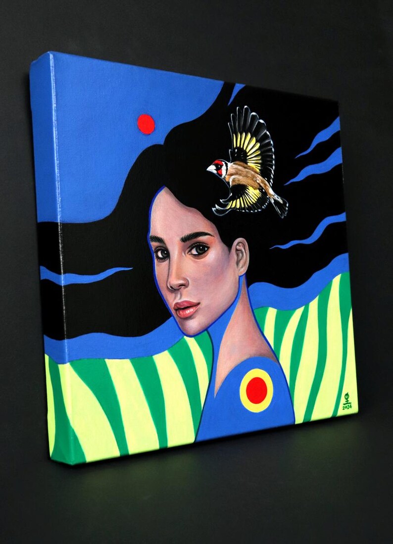 May include: A square canvas painting featuring a portrait of a person with long black hair flowing against a blue and black background. A small goldfinch flies above the head. The lower section displays green and yellow stripes with a red circle.