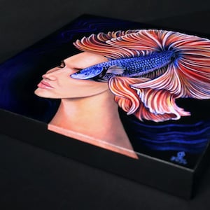 May include: A square canvas print featuring a surreal painting of a human profile merged with a vibrant blue and orange betta fish. The fish's flowing fins extend behind the head against a dark background, creating a striking contrast of colors.