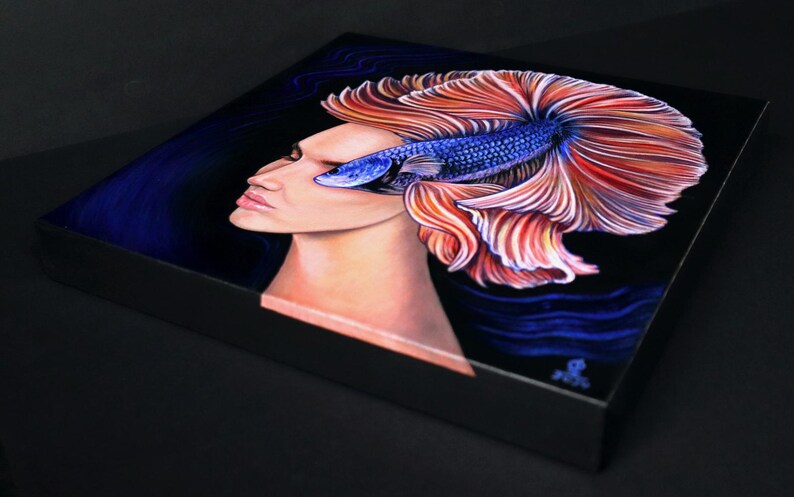 May include: A square canvas print featuring a surreal painting of a human profile merged with a vibrant blue and orange betta fish. The fish's flowing fins extend behind the head against a dark background, creating a striking contrast of colors.