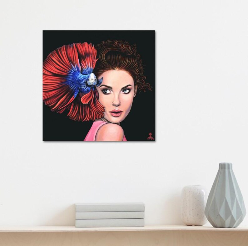 May include: A square wall art print featuring a digital illustration of a person with brown hair looking over their shoulder. A vibrant red and blue betta fish is positioned behind the person's head, with its large, flowing fins fanned out.