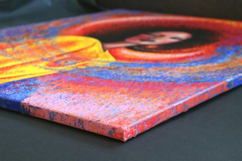 May include: An abstract painting on canvas featuring a woman's face. The artwork uses a vibrant color palette of red, orange, yellow, and blue. The canvas is stretched and mounted, showcasing the side profile of the artwork.
