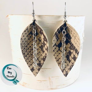 May include: A pair of dangle earrings with a snake skin pattern and a silver chain. The earrings are a light brown color with a darker brown snake skin pattern.