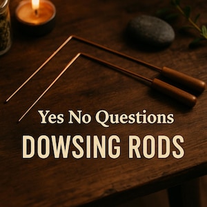 May include: Two copper dowsing rods with wooden handles rest on a dark wooden surface. The text "Yes No Questions" and "DOWSING RODS" are displayed in a cream-colored font. A lit candle and a small stone are in the background.