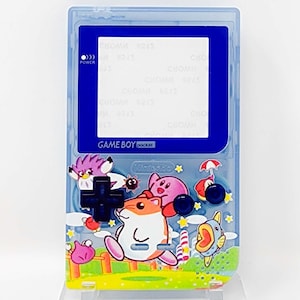 Op de afbeelding: Een blauwe Game Boy Pocket met een doorzichtige plastic behuizing. De voorkant van de Game Boy heeft een kleurrijk ontwerp met personages uit de Kirby-videogameserie. De tekst "GAME BOY pocket" staat op de voorkant van het apparaat.