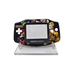 May include: A black Game Boy Advance handheld console featuring a colorful Mario Kart Super Circuit design. The console has a white screen, a directional pad, and the text "GAME BOY ADVANCE". It is displayed on a clear plastic stand.
