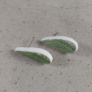 Peut inclure: Une paire de boucles d'oreilles en forme de larme de couleur verte et blanche avec un motif délicat. Les boucles d'oreilles sont en pâte polymère et ont un fermoir argenté.