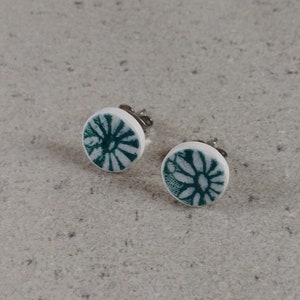 Könnte beinhalten: Ein Paar weiße Ohrstecker mit grünem Blumenmuster.