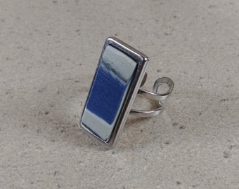 May include: A silver ring with a rectangular blue, white, and gray patterned inlay.