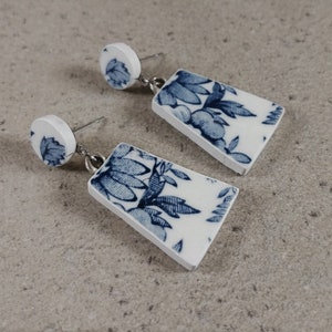 Peut inclure: Une paire de boucles d'oreilles pendantes en porcelaine bleu et blanc avec un motif floral. Les boucles d'oreilles sont faites à partir de porcelaine recyclée.