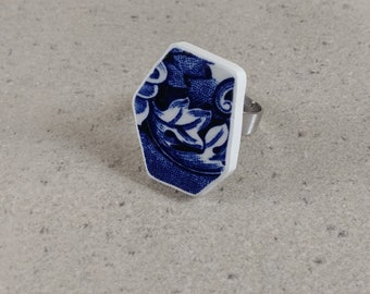 May include: A white ring with a blue and white patterned design. The ring is shaped like a hexagon.
