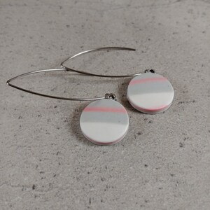 Peut inclure: Une paire de boucles d'oreilles pendantes argentées avec des disques ronds en argile blanche, grise et rose.