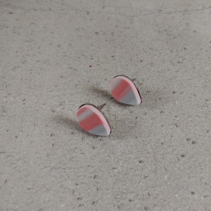 Puede incluir: Un par de pendientes de color rosa y gris en forma de lágrima con postes plateados.