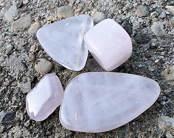 May include: Four pink rose quartz crystals of various shapes and sizes. The crystals are smooth and polished.