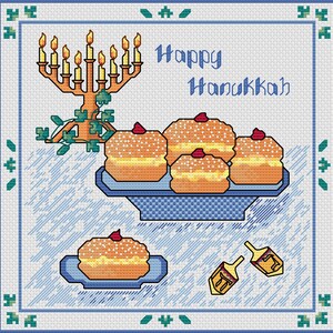 May include: Cross-stitch design featuring a menorah with lit candles, sufganiyot (doughnuts), and dreidels. The words "Happy Hanukkah" are stitched in blue. The image has a blue and white border with decorative elements, celebrating the Jewish holiday.