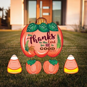 May include: A set of fall-themed yard decorations featuring a large pumpkin with the text "Give thanks to the Lord for HE is GOOD, Psalm 107:1" and three smaller pumpkins shaped like candy corn.