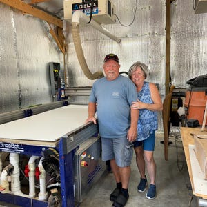 Bruce and Mary Amick standing beside a computerized numerical cutting machine that cuts our yard art signs