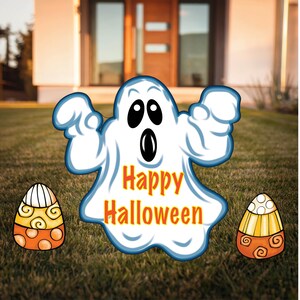 May include: A white ghost with a blue outline and black eyes, holding up its hands. The ghost has the words "Happy Halloween" written on its chest. There are two candy corn decorations on either side of the ghost.