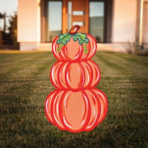 May include: A stack of three orange pumpkins with green stems and leaves. The pumpkins are painted in a realistic style and are arranged in a pyramid shape.