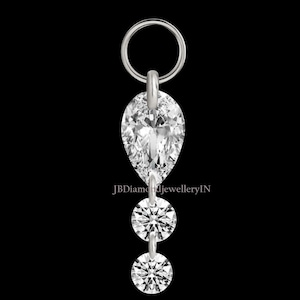 Pode incluir: Pingente prateado com um diamante em forma de pêra e dois diamantes redondos. O pingente tem um pequeno anel na parte superior para fixação. O fundo é preto. O texto "JBDiamondJewelleryIN" é visível.