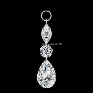 Könnte beinhalten: Ein Anhänger mit drei klaren Edelsteinen: ein Marquise-, ein runder Brillanten- und ein tropfenförmiger Stein. Die Steine sind durch eine silberne Kette verbunden und an einem kleinen Ring aufgehängt. Der schwarze Hintergrund betont das Funkeln der Edelsteine. Der Text "JBDiamondjewelleryIN" ist sichtbar.