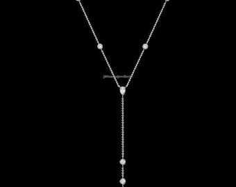 May include: A delicate silver Y-shaped necklace with multiple round and pear-shaped diamond pendants. The necklace features a fine chain and is set against a black background, highlighting the sparkle of the diamonds.