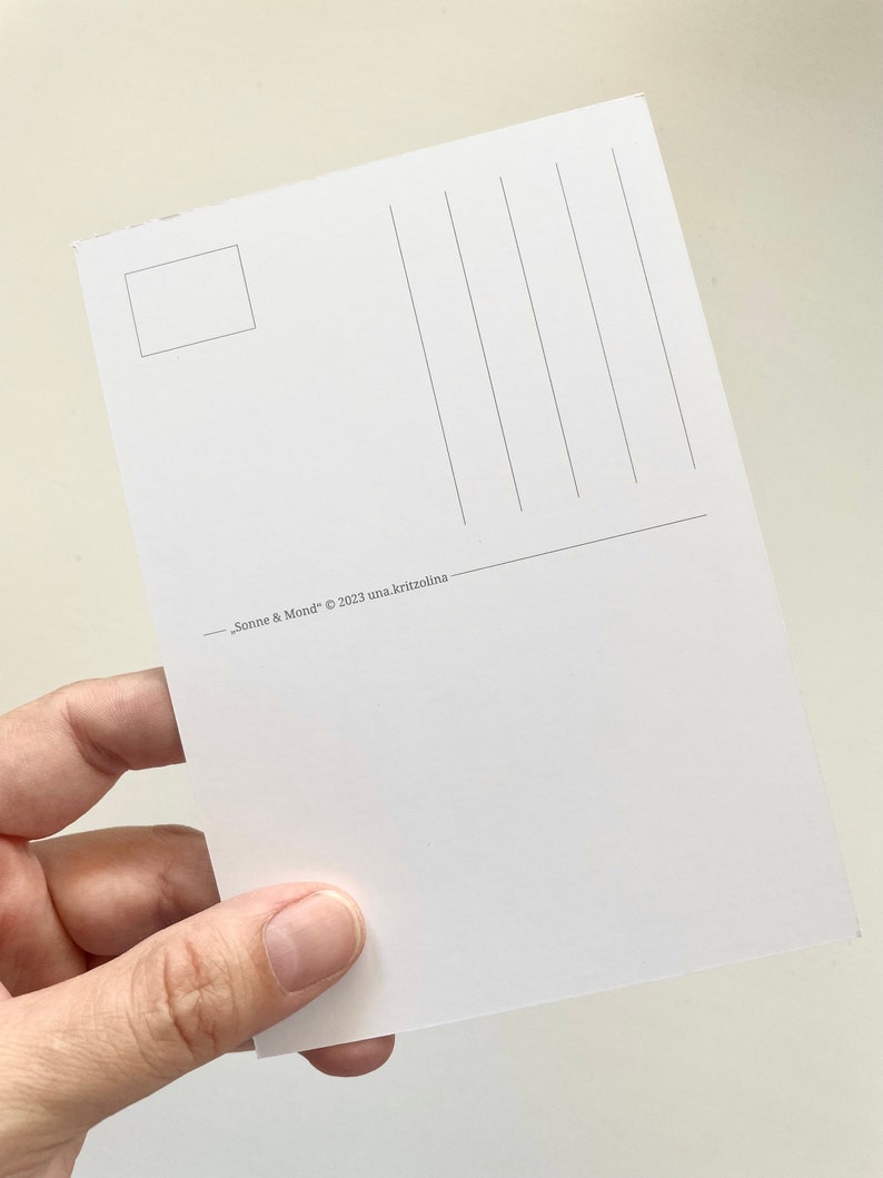 May include: A white postcard with vertical lines for writing and a small rectangle for a stamp. The text "Sonne & Mond" &copy; 2023 una.kritzolina is printed at the bottom. The postcard is held in a hand.