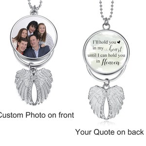 May include: Silver necklace with a round pendant featuring a photo on the front and a quote on the back. The quote reads "I'll hold you in my heart until I can hold you in Heaven". The pendant is attached to a silver chain and has angel wings hanging below.