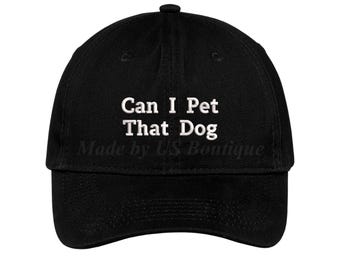 Może przedstawiać: Czarna czapka bejsbolowa z białym napisem "Can I Pet That Dog". Poniżej znajduje się napis "Made by LS Boutique". Czapka ma zakrzywiony daszek i guzik na górze.