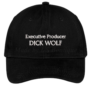 Może przedstawiać: Czarna czapka bejsbolowa z białym napisem "Executive Producer DICK WOLF". Czapka ma również biały napis "Made by LS Boutique". Czapka ma zakrzywiony daszek i guzik na górze.