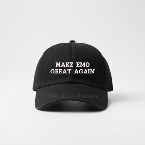 以下が含まれることがあります： 前面に「MAKE EMO GREAT AGAIN」の白い文字が入った黒い野球帽。 つばがカーブしており、丸みを帯びたクラウンが付いています。 つばには「Made by Us Boutique」の文字が白でプリントされています。
