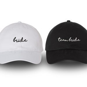 May include: Two baseball caps, one white and one black, with the text "bride" and "team bride" embroidered on them.