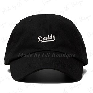 May include: Black baseball cap with a white embroidered "Daddy" text on the front.