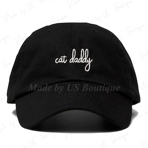 May include: A black baseball cap with a white embroidered phrase "cat daddy" on the front.
